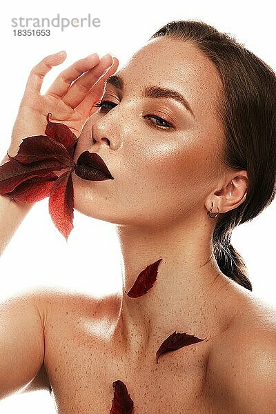 Schönes Mädchen mit klassischem Make-up  roten Lippen und hellem Herbstlaub. Schönheit Gesicht. Bild im Studio auf einem weißen Hintergrund genommen