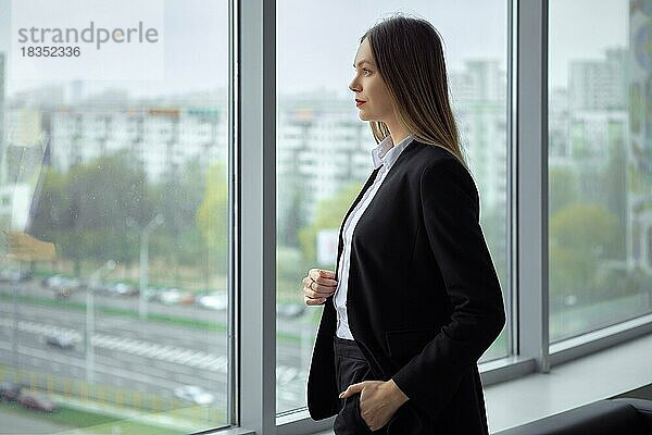 Schöne Geschäftsfrau steht nachdenklich am Fenster