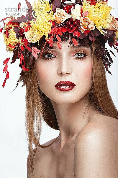 Schönes Mädchen mit hellem Herbstkranz aus Blättern und Blumen. Schönes Gesicht. Bild im Studio auf einem weißen Hintergrund genommen