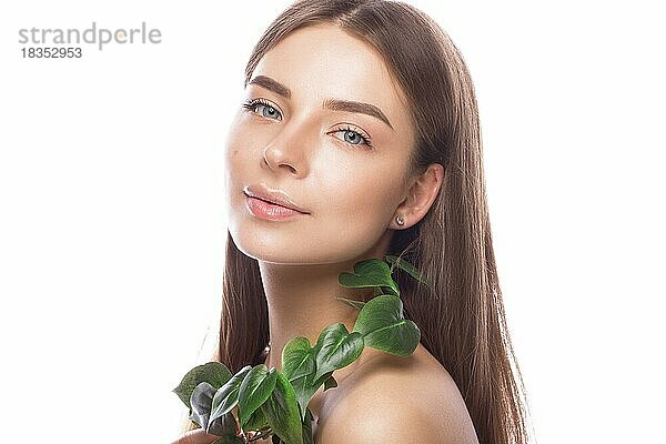Schönes junges Mädchen mit einem leichten natürlichen Make-up und perfekter Haut mit grünem Zweig in der Hand. Schönes Gesicht. Bild im Studio auf einem weißen Hintergrund aufgenommen
