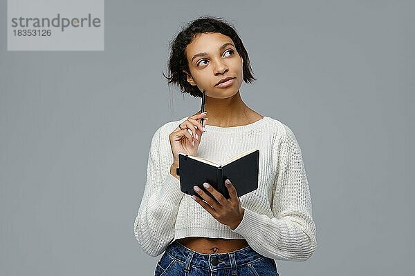 Junge afrikanische Frau erinnert sich an vergangene Ereignisse  um in ein Tagebuch zu schreiben  blickt auf