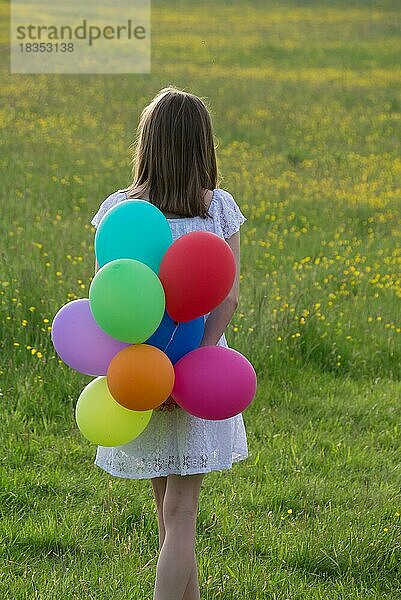 Gilr von hinten mit bunten Luftballons in den Händen  Gegenlicht