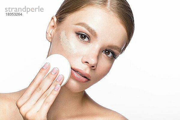 Schönes junges Mädchen mit Schwamm für die Anwendung Make-up und Französisch Maniküre. Schönheit Gesicht. Bild im Studio auf einem weißen Hintergrund genommen