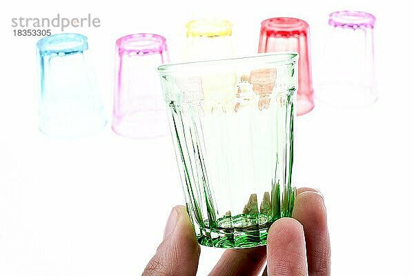 Buntes Trinkglas in der Hand mit Gläsern auf weißem Hintergrund