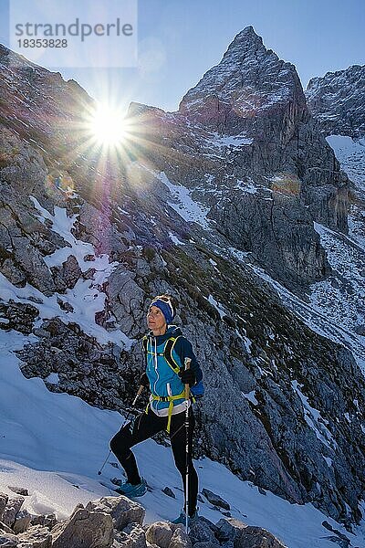 Bergsteigerin steigt im verschneiten  felsigen Gelände nach oben  hinten die Blaueisspitze  Hochkalter  Nationalpark Berchtesgaden  Ramsau  Berchtesgadener Land  Oberbayern  Bayern  Deutschland  Europa