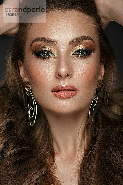 Schönes Mädchen mit hellen modischen Make-up und ungewöhnliche Gold-Accessoires. Schönes Gesicht. Foto im Studio aufgenommen