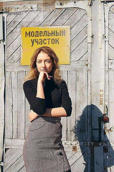 Attraktives Mädchen in der Nähe der Fabrik Tür mit Warntafeln. (Inschrift auf Platte ist auf Russisch kann als Modell Bereich übersetzt werden und nicht betreten)
