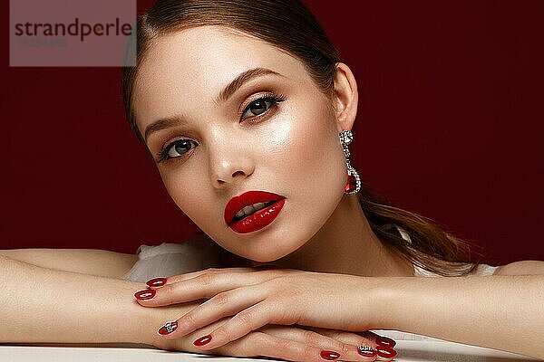 Schönes Mädchen in rotem Kleid mit klassischem Make-up und roter Maniküre. Schönes Gesicht. Foto im Studio aufgenommen