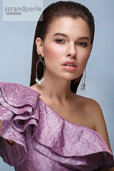 Schönes frisches Mädchen mit klassischem Make-up  glatten Haaren in einem lila Kleid. Schönes Gesicht. Foto im Studio aufgenommen