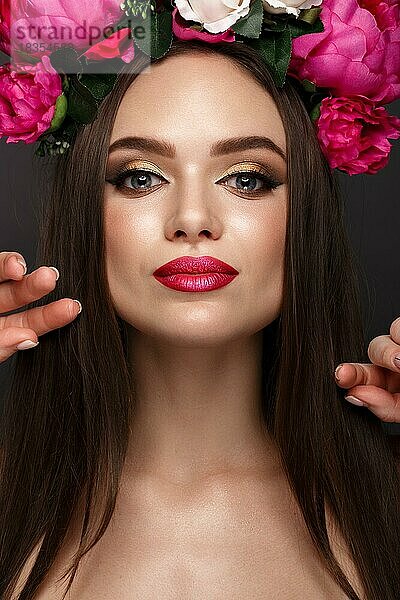 Schönes Mädchen mit hellem Make-up und Blumen auf dem Kopf. Schönes Gesicht. Fotos im Studio geschossen