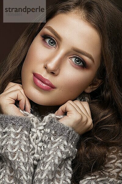 Schönes junges Mädchen mit sanftem Make-up im warmen Pullover und langen glatten Haaren. Schönes Gesicht. Studio Porträt
