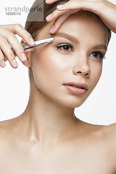 Schönes junges Mädchen mit leichtem Natur-Make-up  Augenbrauenpinzette und französischer Maniküre. Schönes Gesicht. Bild im Studio auf einem weißen Hintergrund aufgenommen