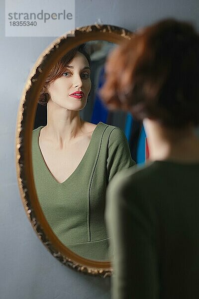 Porträt einer selbstbewussten  stilvollen Dame  die in den Wandspiegel schaut. Fokus auf Reflexion