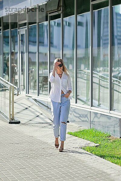 Streetstyle-Mode  Dame in weißem Hemd und Boyfriend-Jeans beim Spaziergang im Geschäftszentrum