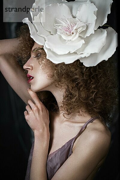 Schönes Mädchen mit lockigem Haar in Dessous mit großer Blume. Die Schönheit des Gesichts. Fotos im Studio geschossen