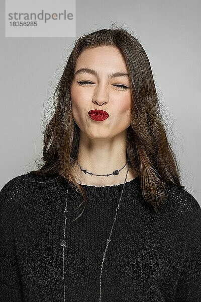 Wunderschöne Model-Dame mit natürlichem Make-up und brünetten Haaren. Studio-Modeaufnahme auf grauem Hintergrund  perfekte Haut  matte rote Lippen