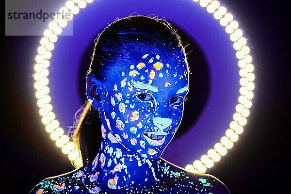 Porträt eines schönen Mädchens mit ultravioletter Farbe im Gesicht. Mädchen mit Neon-Make-up in Farbe Licht