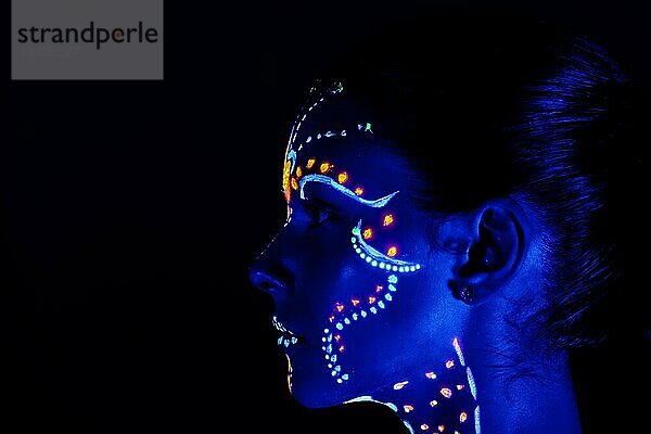 Porträt eines schönen Mädchens mit ultravioletter Farbe im Gesicht. Mädchen mit Neon-Make-up in Farbe Licht