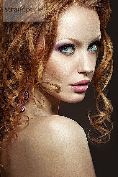 Schönes rothaariges Mädchen mit hellem Make-up und Locken. Bild im Studio auf einem schwarzen Hintergrund aufgenommen