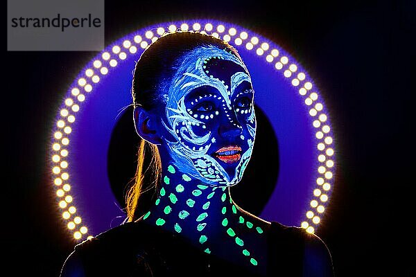 Porträt eines schönen Mädchens mit ultravioletter Farbe im Gesicht. Mädchen mit Neon-Make-up in Farbe Licht