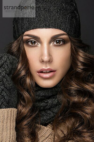 Schönes Mädchen mit Smokey-Make-up  Locken in schwarzer Winter-Strickmütze. Warmes Winterbild. Schönes Gesicht. Bild im Studio aufgenommen