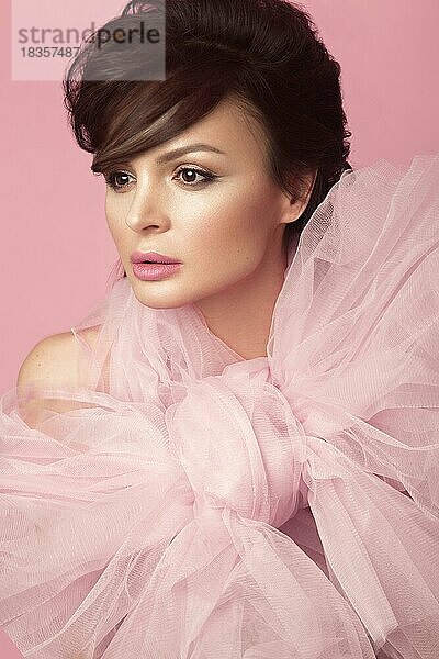 Mode schöne Frau im schwarzen Kleid mit Schleife  Retro-Make-up und Haar. Schönheit Gesicht und Körper. Foto im Studio auf einem rosa Hintergrund genommen