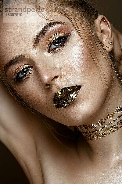 Schönes Mädchen mit einem goldenen glänzenden Make-up und Sternen auf ihren Lippen. Schönes Gesicht. Foto im Studio aufgenommen