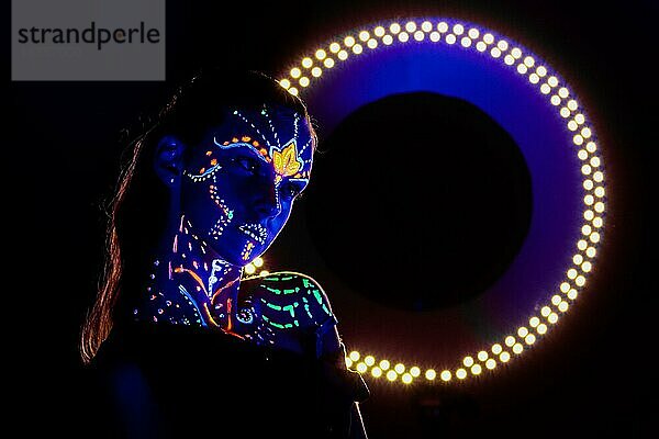 Porträt eines schönen Mädchens mit ultravioletter Farbe im Gesicht. Mädchen mit Neon-Make-up in Farbe Licht