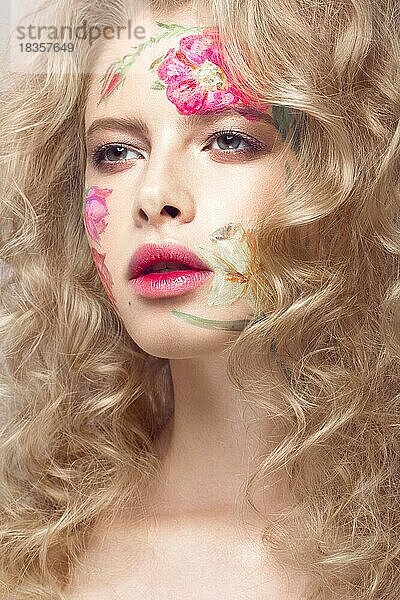 Schönes blondes Mädchen mit Locken und einem Blumenmuster auf dem Gesicht. Schönheit Blumen. Porträtaufnahme im Studio