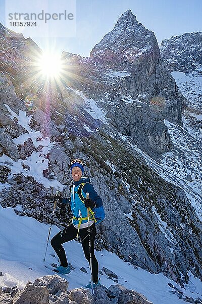 Bergsteigerin steigt im verschneiten  felsigen Gelände nach oben  hinten die Blaueisspitze  Hochkalter  Nationalpark Berchtesgaden  Ramsau  Berchtesgadener Land  Oberbayern  Bayern  Deutschland  Europa