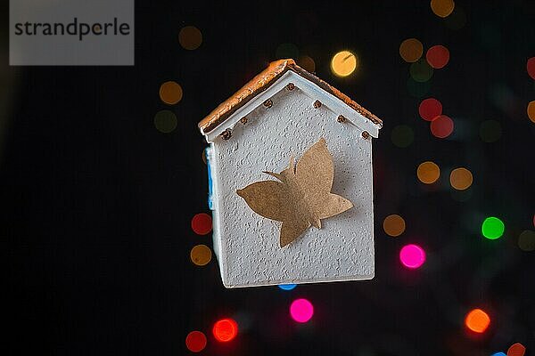 Papier Schmetterling auf einem Modell Haus auf einem Bokeh Licht