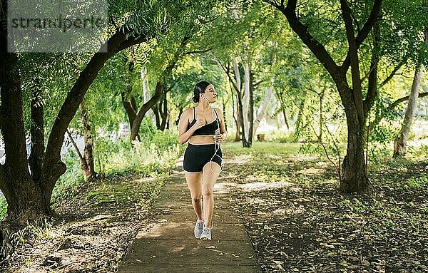 Gesunder Lebensstil Konzept einer Frau joggt in einem grünen Park  Sportliche junge Frau läuft in einem Park. Mädchen  das in einem Park läuft  während es Musik hört  Lifestyle einer sportlichen Frau  die in einem Park läuft