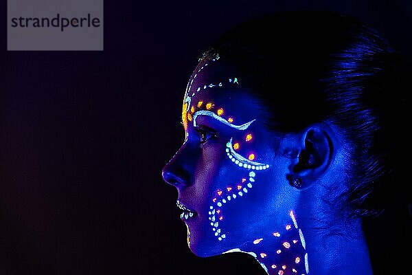 Porträt eines schönen Mädchens mit ultravioletter Farbe im Gesicht. Mädchen mit Neon-Make-up in Farbe Licht