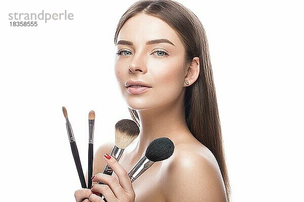 Schönes junges Mädchen mit einem leichten natürlichen Make-up  Pinsel für Kosmetik und perfekte Haut. Schönheit Gesicht. Bild im Studio auf einem weißen Hintergrund genommen