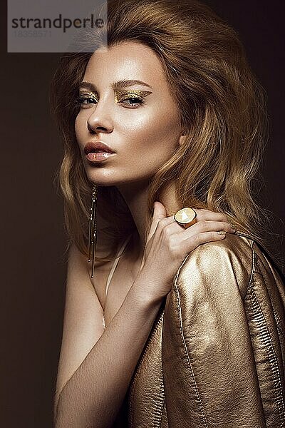 Schönes Mädchen in einem goldenen Kleid mit kreativen Make-up und Haar. Die Schönheit des Gesichts. Fotos im Studio geschossen