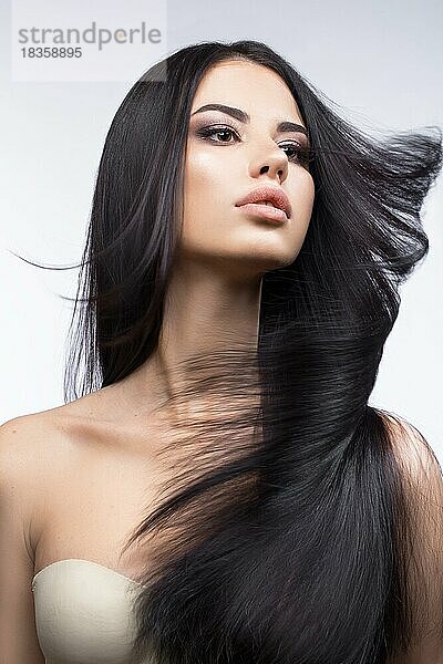 Schönes brünettes Mädchen in Bewegung mit einem perfekt glatten Haar  und klassisches Make-up. Schönheit Gesicht. Bild im Studio auf einem weißen Hintergrund genommen