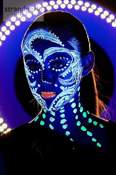 Porträt eines schönen Mädchens mit ultravioletter Farbe im Gesicht. Mädchen mit Neon-Make-up in Farbe Licht