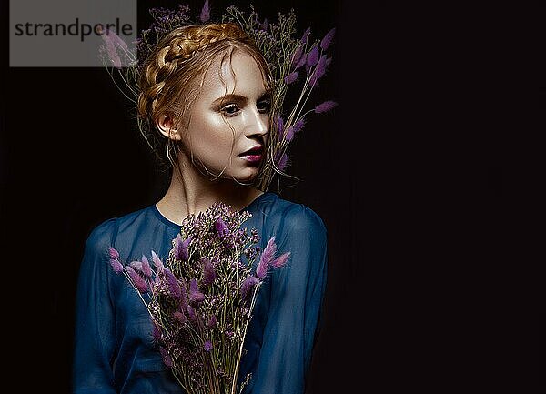 Schönes Mädchen mit einem sanften Make-up und Frisur in Form von Zöpfen  trockene Blumen in ihren Händen. Schönes Gesicht. Bild im Studio aufgenommen