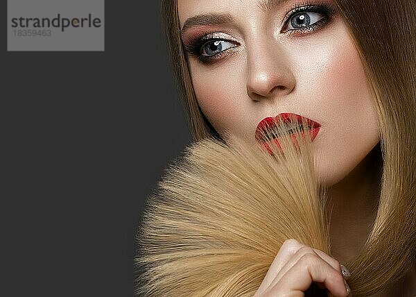 Schönes blondes Mädchen mit perfekt glattem Haar  klassischem Make-up und roten Lippen. Schönes Gesicht. Bild im Studio auf einem weißen Hintergrund genommen