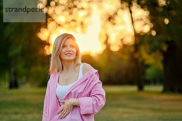Positive junge Frau im Freien im Park bei Sonnenuntergang