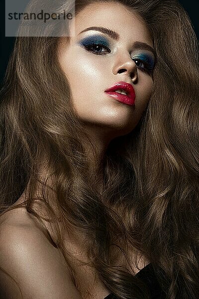Schönes Mädchen in Hollywood-Manier mit Locken  roten Lippen und blauem Make-up. Schönes Gesicht und Haare. Bild im Studio aufgenommen