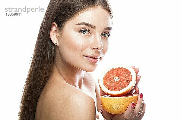 Schönes junges Mädchen mit einem leichten natürlichen Make-up und perfekter Haut mit Grapefruit in der Hand. Schönes Gesicht. Bild im Studio auf einem weißen Hintergrund aufgenommen