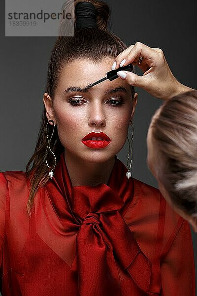 Schönes frisches Mädchen mit klassischem Make-up  glatten Haaren in einem roten Kleid. Schönes Gesicht. Foto im Studio aufgenommen