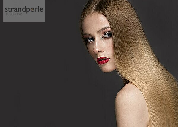 Schönes blondes Mädchen mit perfekt glattem Haar  klassischem Make-up und roten Lippen. Schönes Gesicht. Bild im Studio auf einem weißen Hintergrund genommen