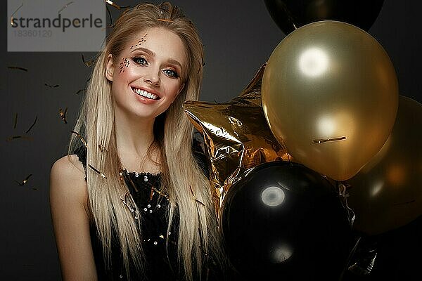 Schönes junges Mädchen in elegantem Abendkleid mit festlichen Luftballons. Schönes Gesicht. Foto im Studio aufgenommen