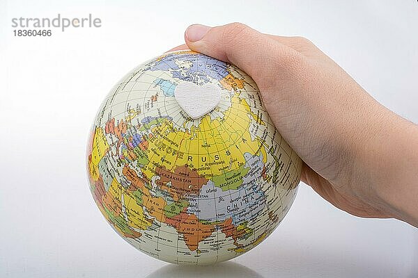 Eine Hand hält einen Globus mit einer Karte in der Hand
