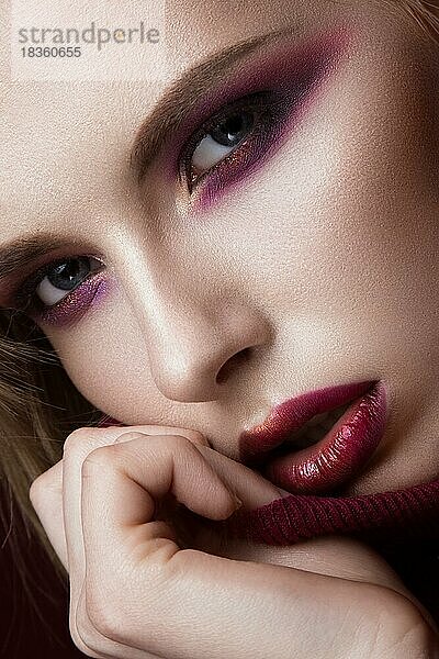 Schöne blonde Frau in einem roten Pullover mit hellem Make-up und dunklen Lippen. Schönes Gesicht. Foto im Studio aufgenommen. Porträt in Nahaufnahme