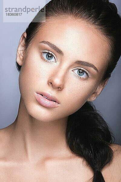 Schönes junges Mädchen mit einem leichten natürlichen Make-up. Schönes Gesicht. Bild im Studio auf einem grauen Hintergrund aufgenommen