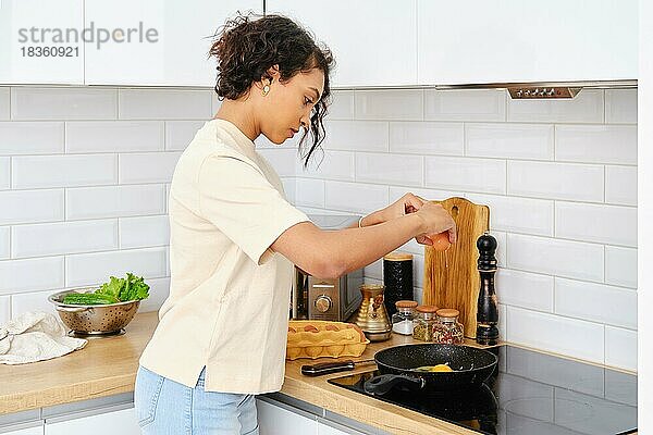 Afroamerikanische Frau brät Rührei zum Frühstück in der Küche
