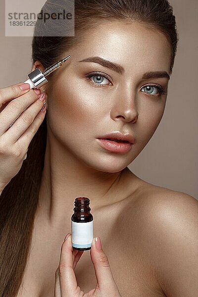 Schönes junges Mädchen mit natürlichen nude Make-up mit Kosmetik in den Händen. Schönes Gesicht. Foto im Studio aufgenommen